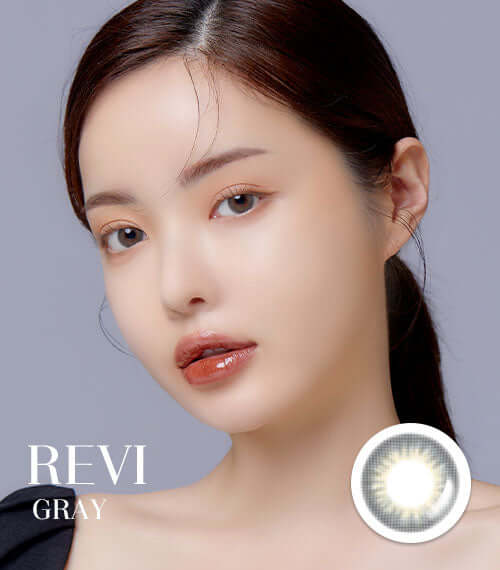 Woman wearing Revi Gray toric contact lenses showcasing transparent gray color for small eyes with a replacement schedule variation.